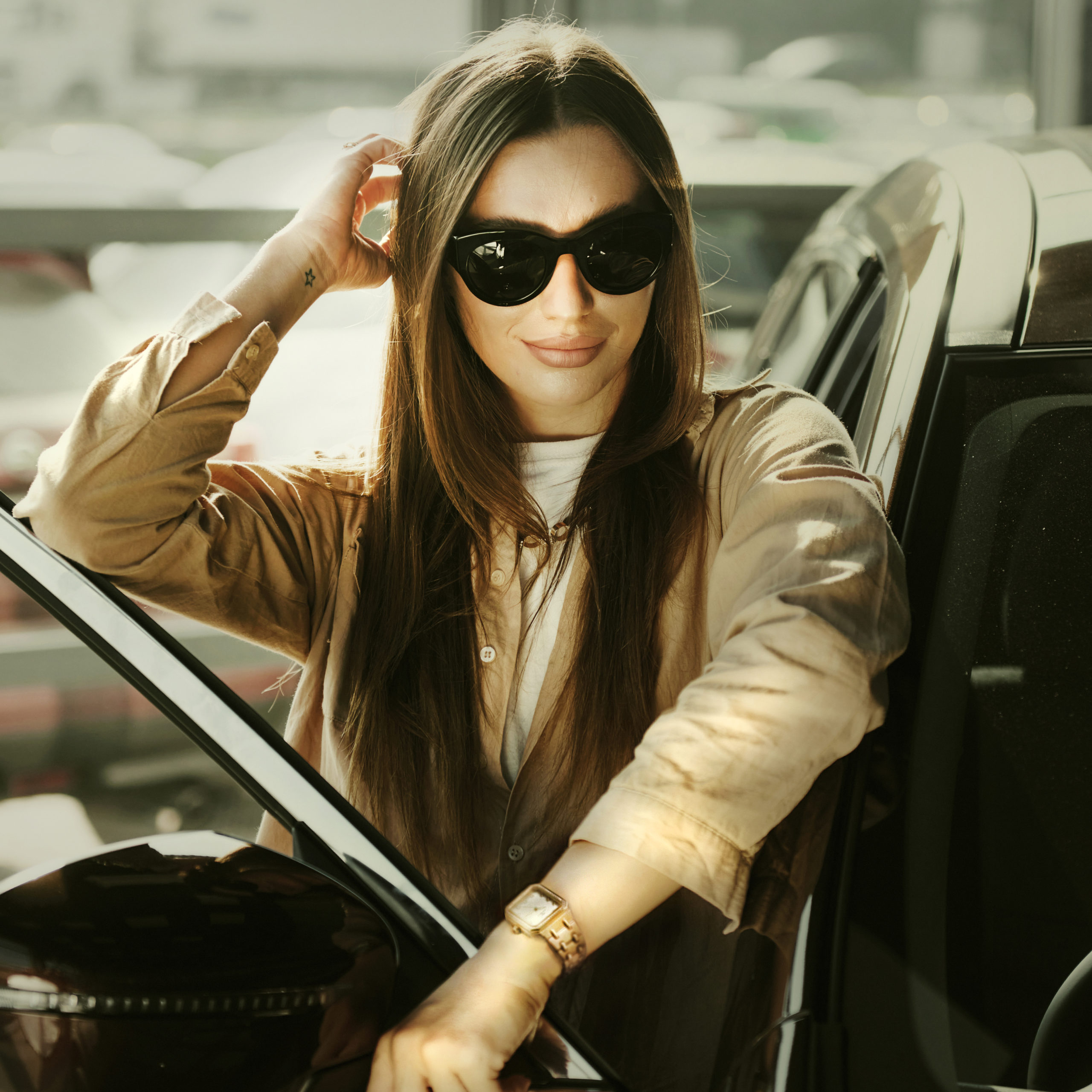 Sits with car's window opened. Fashionable beautiful young woman and her modern automobile